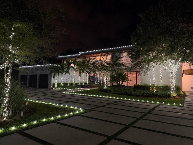 A home with a path-lit driveway and wrapped palms, Pinecrest