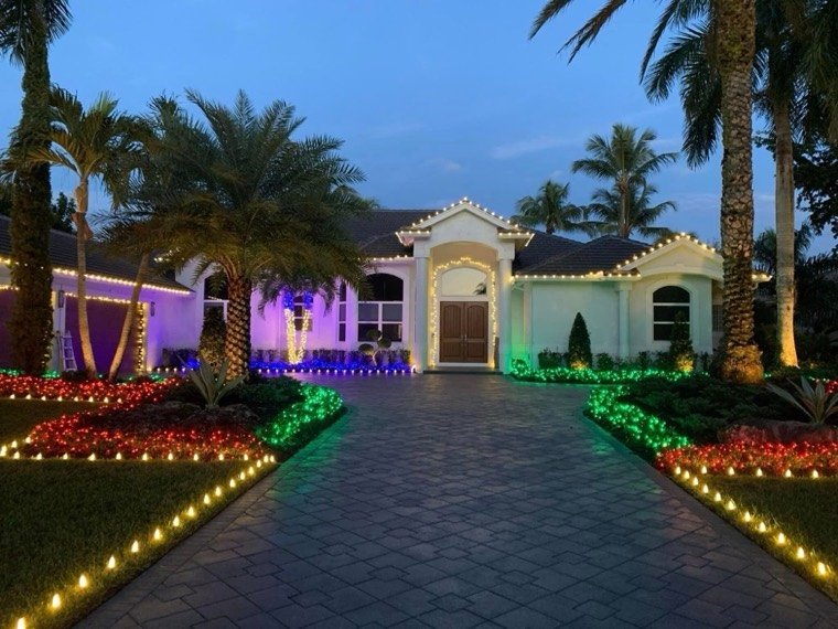 A home at dusk with warm-white roofline and colored garden beds, Weston